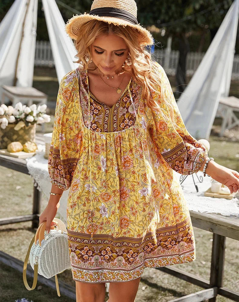 Yellow bohemian mini dress with sleeves, featuring a flowy design perfect for a laid-back summer look.