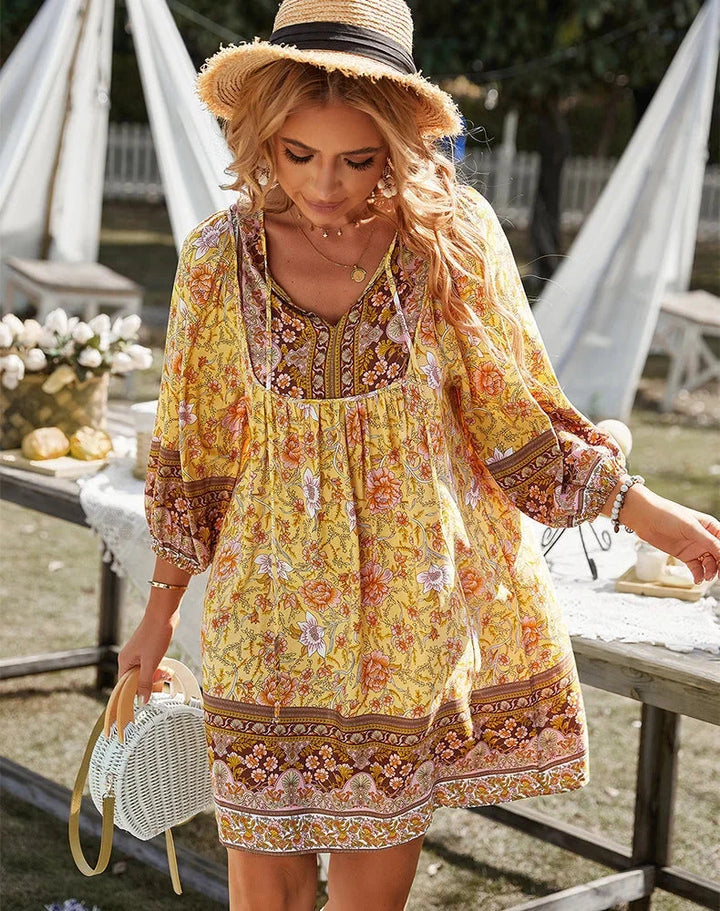 Yellow bohemian mini dress with sleeves, featuring a flowy design perfect for a laid-back summer look.