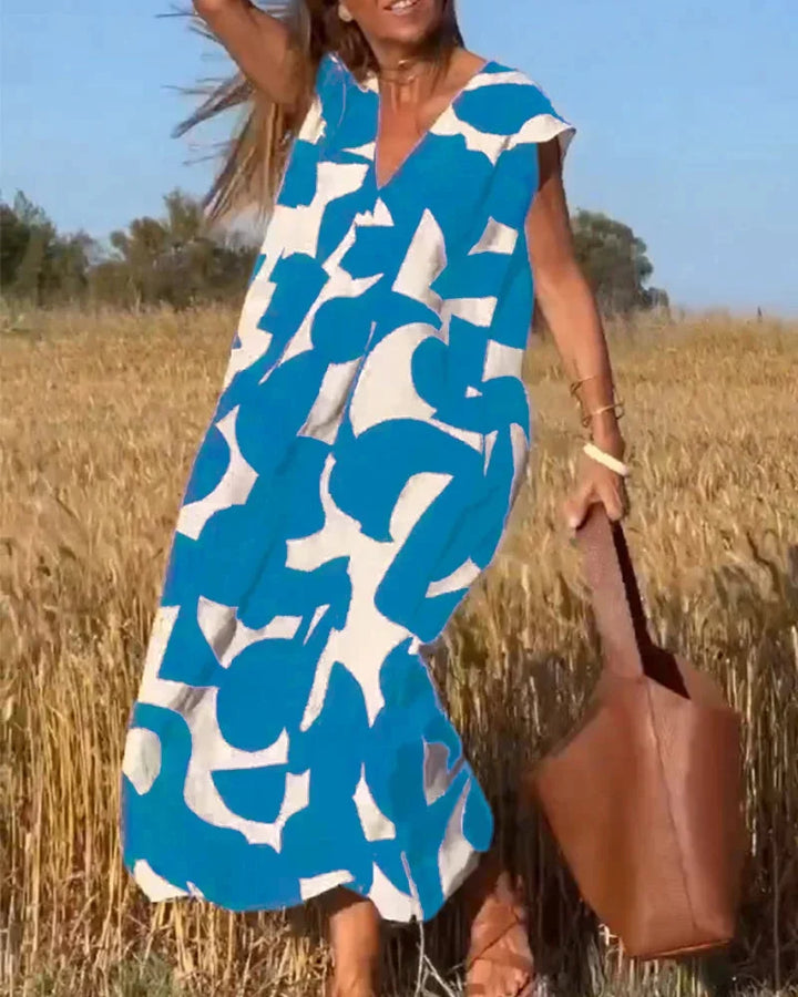 Blue flowy V-neck maxi dress with bold patterns. Made of soft, breathable fabric perfect for all-day comfort and style.