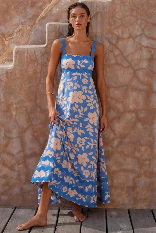 Sleeveless blue maxi dress with wave trim detail, made of soft flowing fabric. Ideal for casual or dressy occasions.