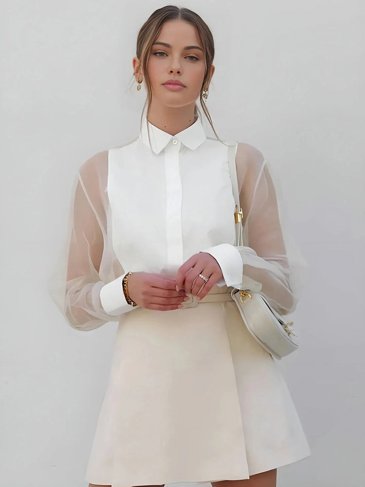 White mini dress with sheer long sleeves and collared neckline by Bentley. Elegant and feminine design perfect for any…