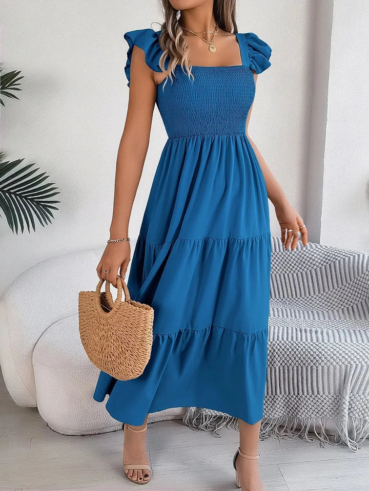 Blue midi dress with tiered ruffle detailing and smocked bodice. Perfect for a casual yet stylish look.