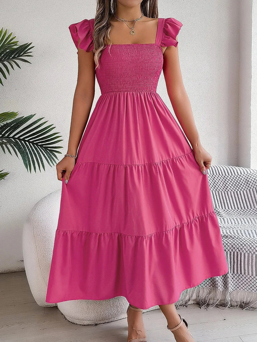 Pink tiered ruffle midi dress with smocked bodice. Soft, flowy fabric perfect for summer days or special occasions.