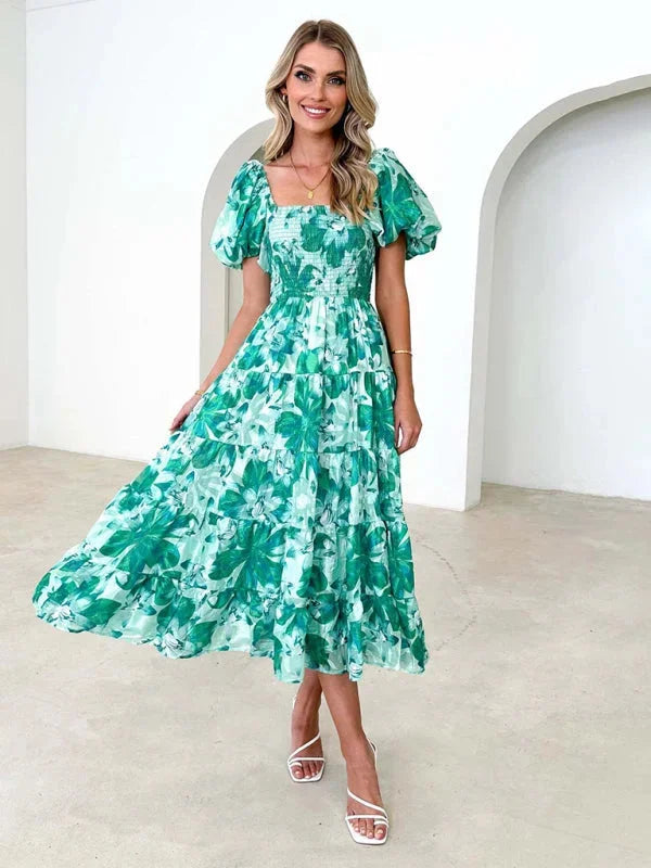 Green tiered summer dress with flowing floral design, perfect for a breezy day. Made of lightweight and breathable fabric.