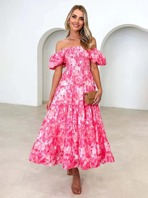 Pink tiered summer dress with flowing floral pattern. Lightweight fabric ideal for warm weather. Flattering fit for casual…