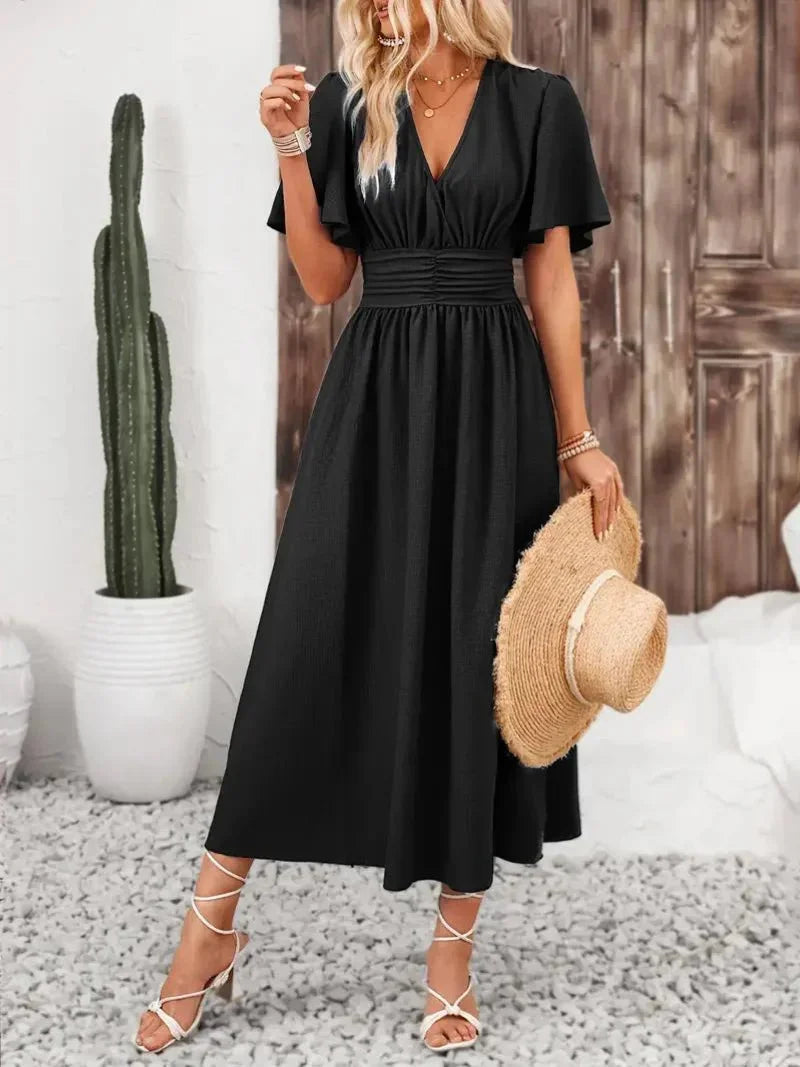 Black V-neck sundress with ruffled sleeves by Cimani. Soft cotton blend fabric with a flattering silhouette for a chic…