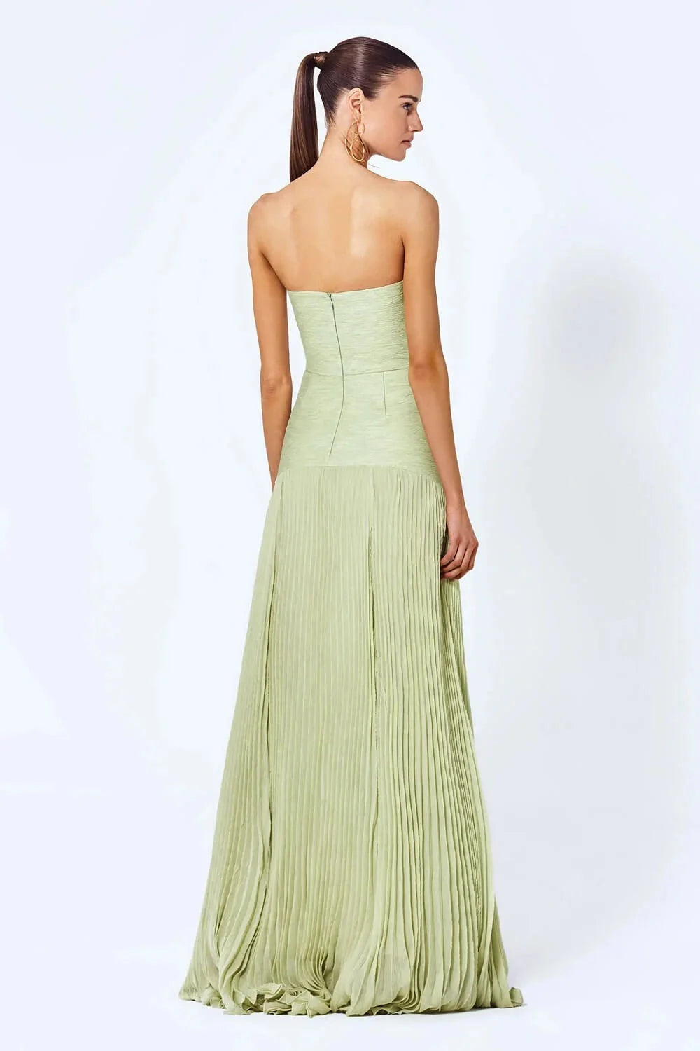 Light green strapless pleated maxi dress in elegant design on a white background wearing by a model.