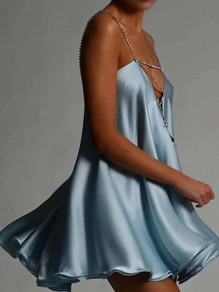 Blue satin dress with embellished chains, fluid design.