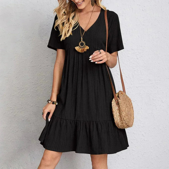 Black V-neck mini dress with ruffle hem, made from soft and flowy fabric. Flattering fit with a feminine touch.