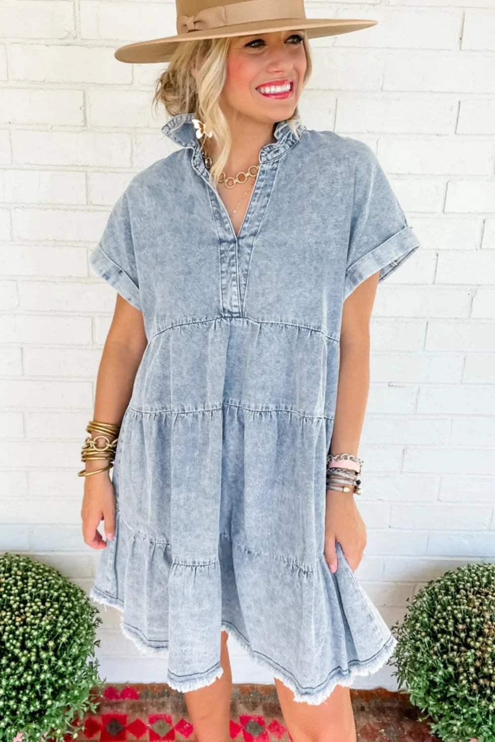 "Denim V-neck dress with acid-wash effect, sleeveless design, and knee-length cut on mannequin."