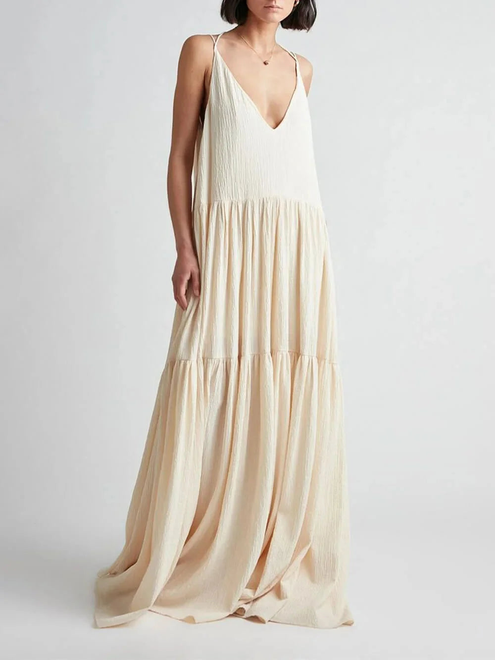 "Sand-colored V-neck maxi dress with tiered skirt showcasing a flowing design by Jeilani. Perfect for a casual yet elegant…