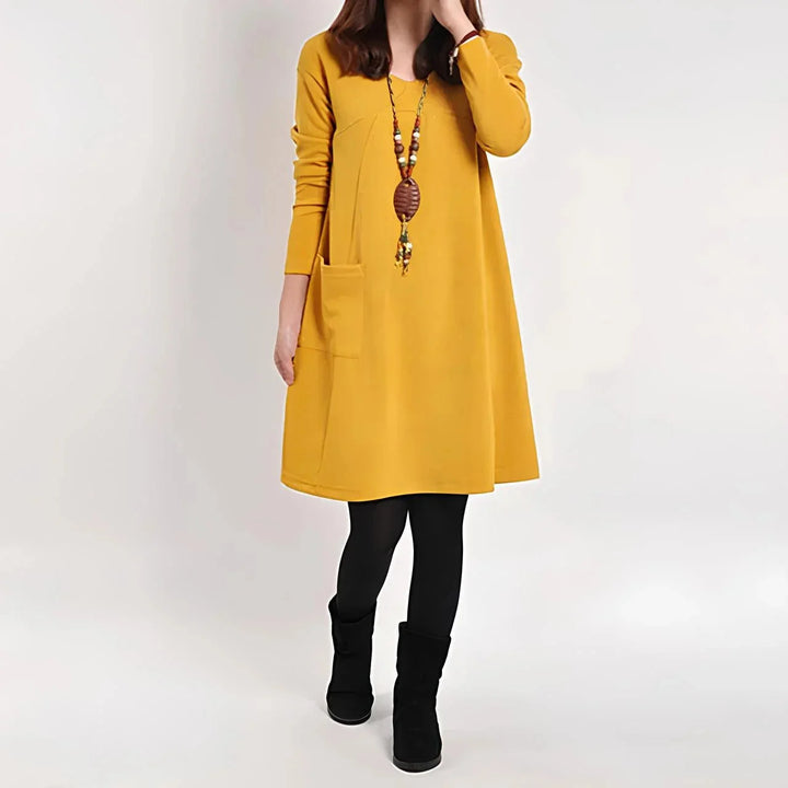 "Yellow shift dress with pockets, long sleeves, and a relaxed fit, made from a soft and comfortable fabric."