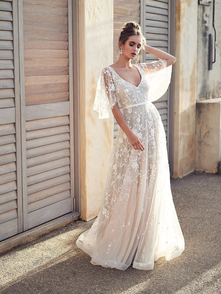 "White embroidered maxi dress with flutter sleeves, elegant design in airy fabric for a chic summer look by Kenzleigh."