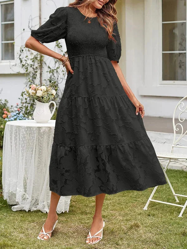 "Black tiered midi dress with floral textured pattern, perfect for all occasions."