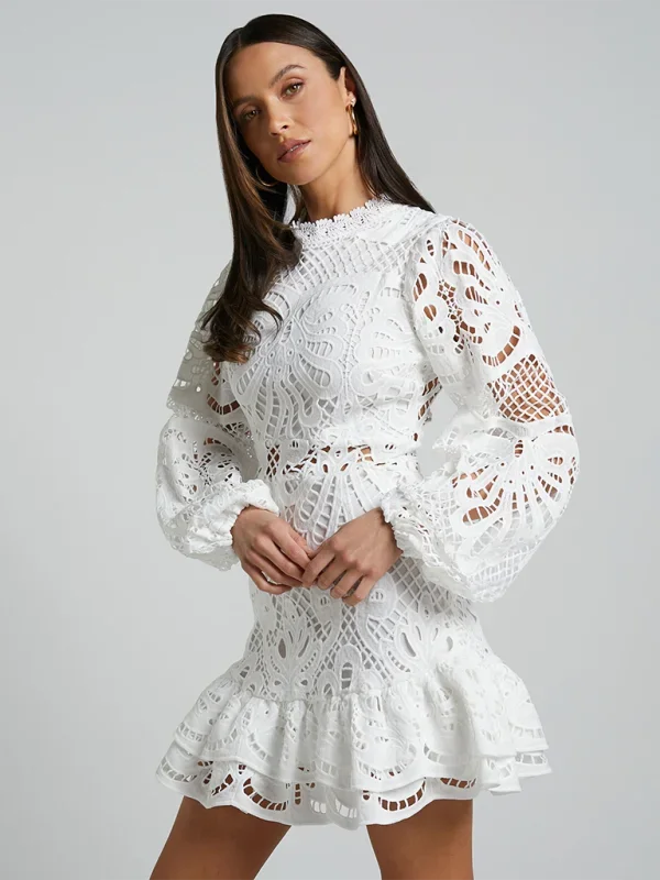 White lace mini dress with ruffled long sleeves. Elegant design perfect for special occasions or evening events.