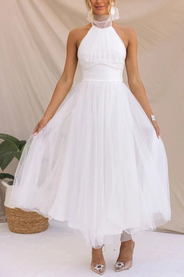 White halter neck pleated midi dress exuding elegance with its flowing silhouette and gentle folds.