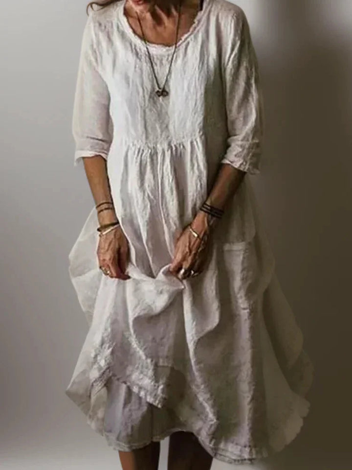 White V-neck tiered maxi dress with 3/4 sleeves in soft, breathable fabric. Elegant and versatile style for any occasion.