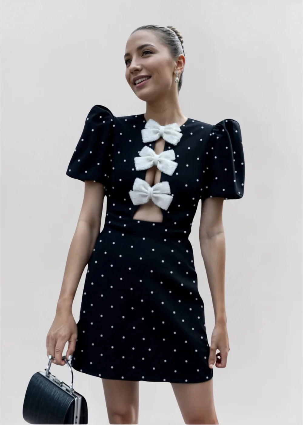 Black mini dress with puff sleeves, adorned with pearls and bows. Feminine and elegant design perfect for special occasions.