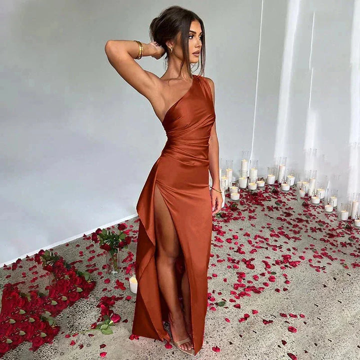 Brown one-shoulder maxi dress with thigh slit. Made of flowing fabric. Elegant design for a chic look.