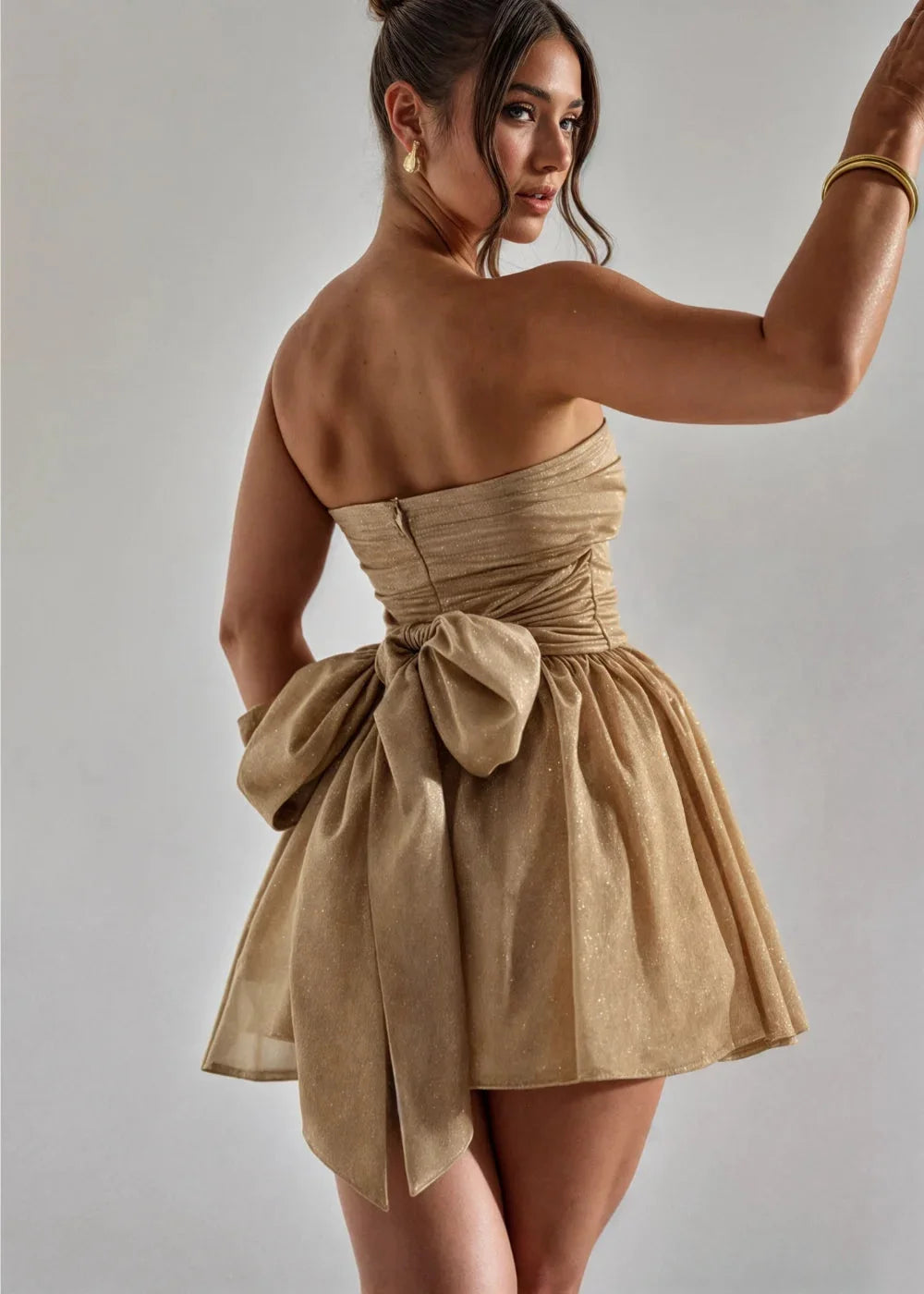 Gold strapless mini dress with a feminine bow accent. Made of silky fabric, perfect for a sunny day out.