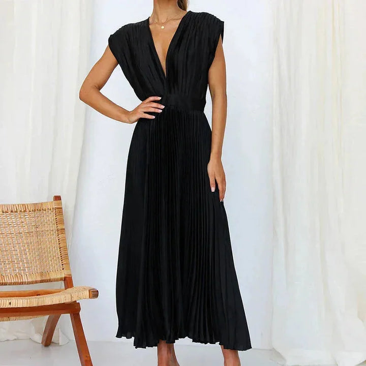 Navy blue pleated dress with deep V-neckline, perfect for formal occasions, made of soft, flowy fabric.