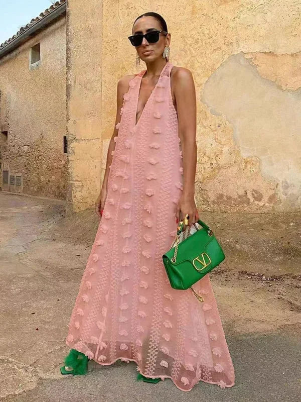 Pink halter neck maxi dress with intricate floral details. Flowy and feminine, ideal for a chic daytime look or dressed up…