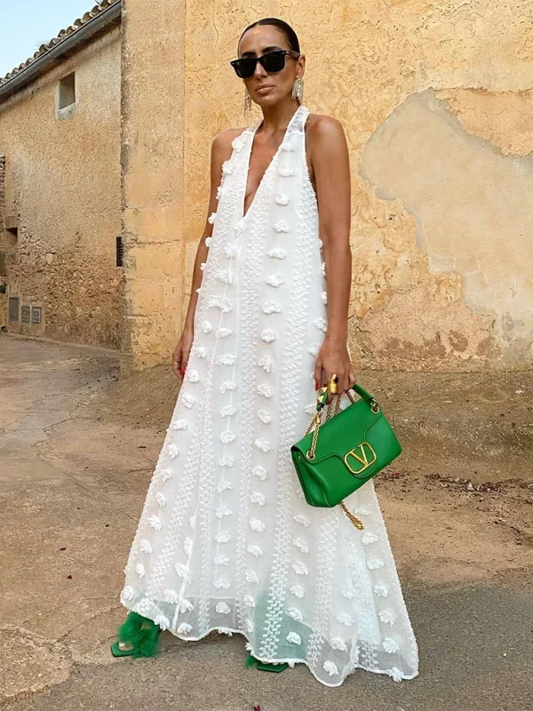 White halter neck maxi dress with delicate floral embroidery, perfect for a breezy summer day.