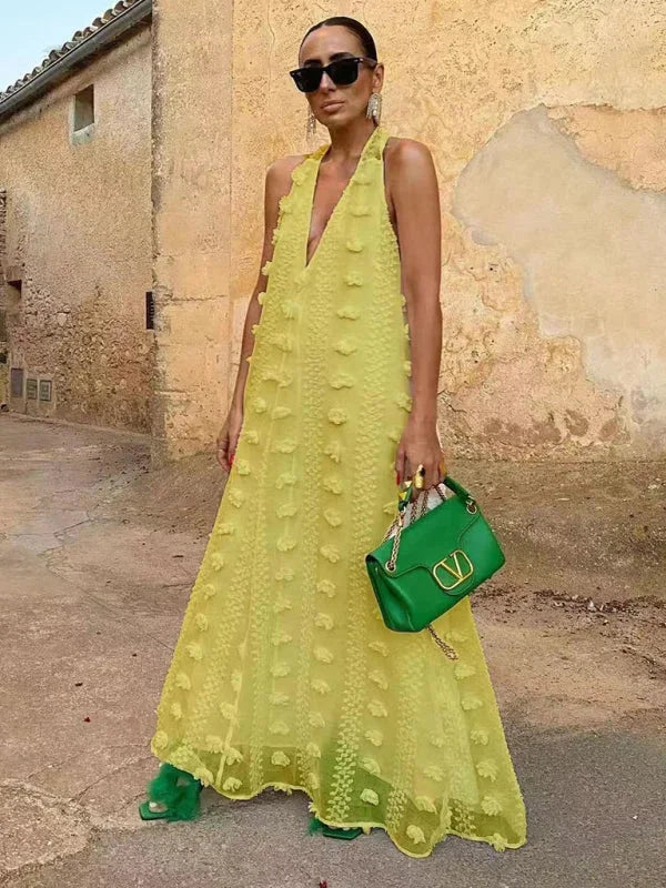 Yellow halter neck maxi dress featuring delicate floral details. Made of flowy fabric perfect for summer days and outings.